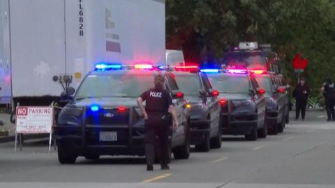 Police cars are seen in a line with red and blue flashing lights.