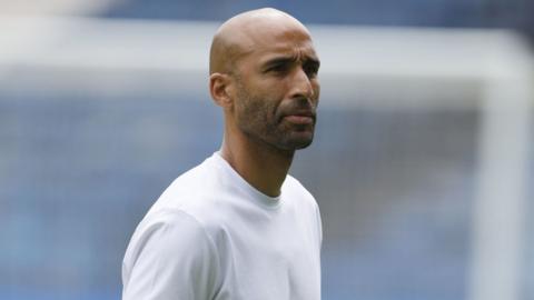 Lee Grants looks ahead with a focused look. he wears a white t shirt