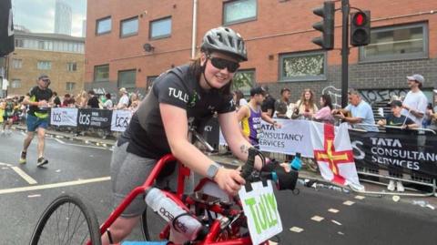 Tully Kearney, wearing a cycling helmet and shades, runs using her red-coloured three wheel frame 