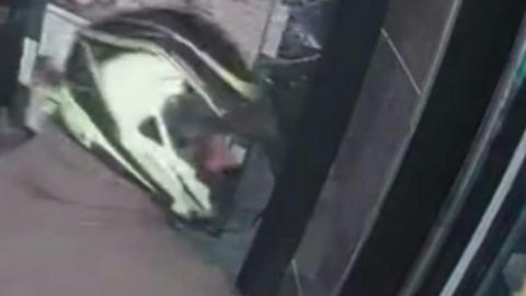 A CCTV image of a man in a black and white crash helmet