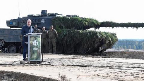 German Chancellor Olaf Scholz delivers a speech in front of a Leopard 2 tank in October 2022