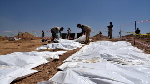 Iraqi forensic personnel exhumes bodies at a mass grave where inmates of Badoush prison were killed by the Islamic State group, in al-Humaydat village, western Mosul, Iraq (13 June 2021)