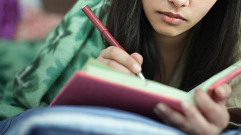 Stock photo of a young person writing in a diary