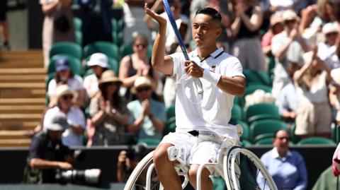 Tokito Oda raises his racquet in celebration of winning a point