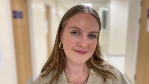 Picture of Eliza standing in a hospital corridor