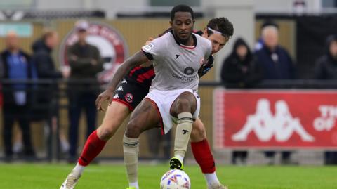 Rolando Aarons challenges for the ball with Shaun Donnellan of Truro City.