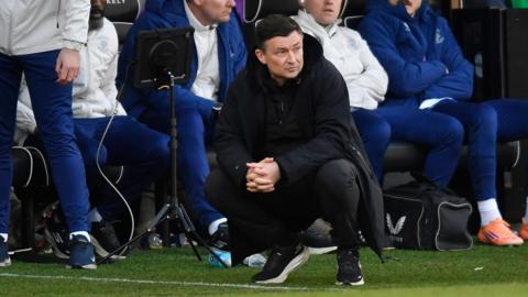 Paul Heckingbottom crouching down in the Preston technical area looking concerned
