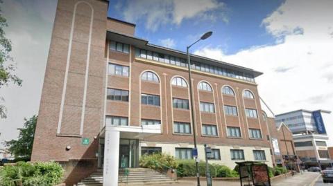 The outside of Consort House in Redhill which is a large brick building with rounded windows