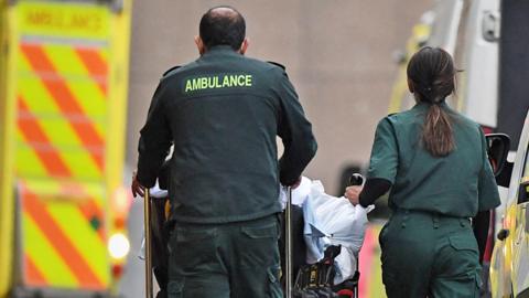 Paramedics wheel a patient on a trolley outside the Royal London hospital in London on January 12, 2021