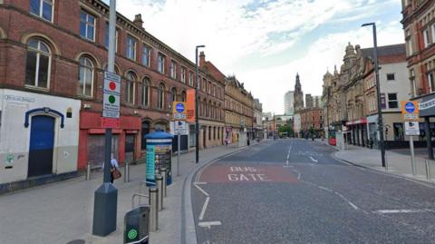 A road through a city centre with buildings on each side. 