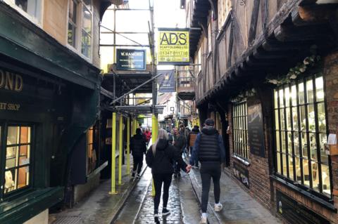 People walking along the Shambles street in York with Scaffolding which has gone up