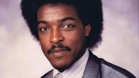 A head and shoulders studio portrait shot of a young Dawit Isaak