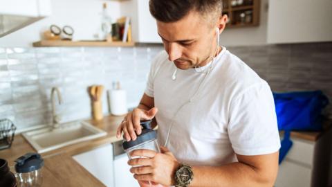 A man in his kitchen with a protein shake