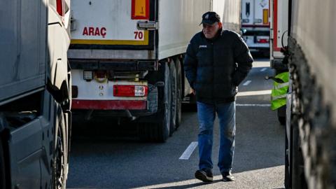 A trucker walks between trucks at a border crossing between Bulgaria and Romania