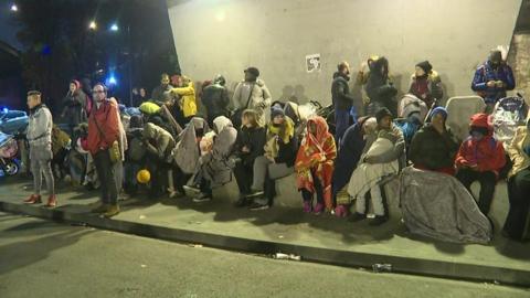 Migrants sit around as camp is cleared in Paris