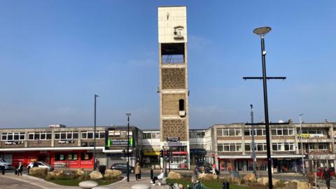 A six-storey concrete tower with a white-tiled clock face at the top 