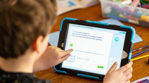 Wilfred, aged 7, does maths activities on an iPad as he takes part in home schooling