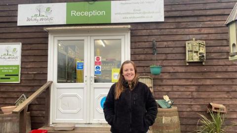 A woman stands in front of the reception entrance at Whitby Wildlife Sanctuary.