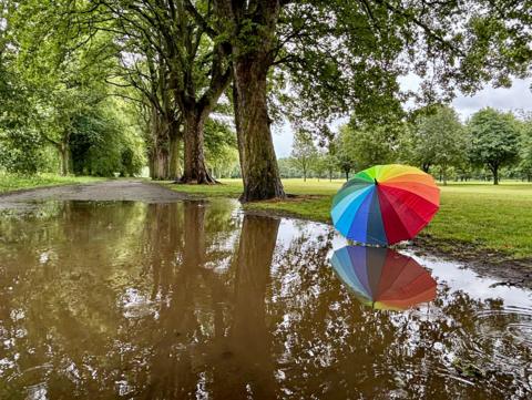 Flooding in a park with a multi-coloured umbrella on the edge of the water