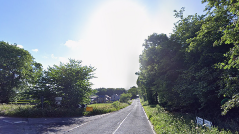 The A5012, a long and straight tree-lined country road with a turn off to the left-hand side