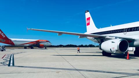 An easyJet plan and BEA plan sit on a runway in the sunshine.