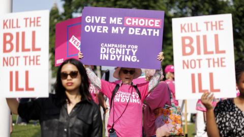 Campaigners and demonstrators in favour and against the assisted dying bill hold placards as they gather in Parliament Square in London