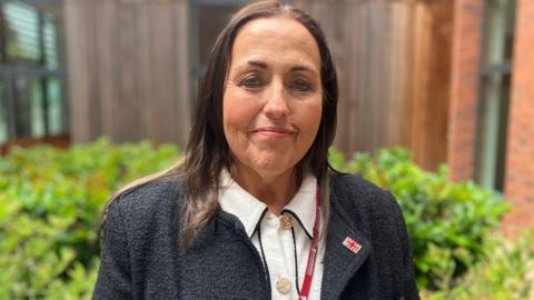 A woman wearing a black jumper and white top, as well as a Worcestershire County Council lanyard.