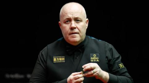 John Higgins puts chalk on the tip of his snooker cue