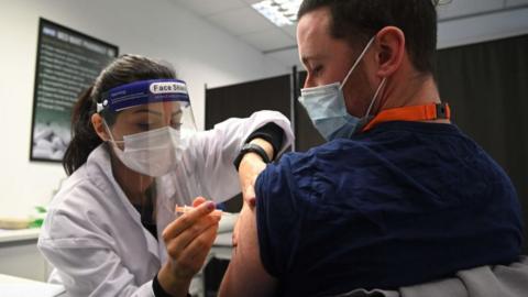 A care worker being vaccinated at a pharmacy in Borehamwood