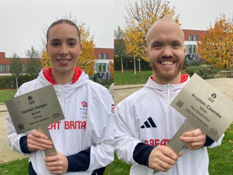 A man and a woman in Team GB and Paralympics GB tracksuits smile at the camera holding plaques with their names on