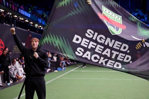 AngryGinge holds a flag that reads 'Signed. Defeated. Sacked'.