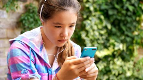 A teenager looks at her phone with concern