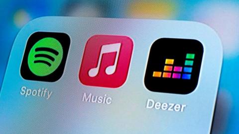 Three icons of music apps on iPhone, Spotify, Apple Music, and Deezer