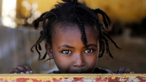 An Ethiopian girl stands at the window of a temporary shelter.