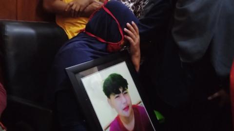 Susiana, the mother of one of the victims cries in the courtroom as she holds a photo of her son