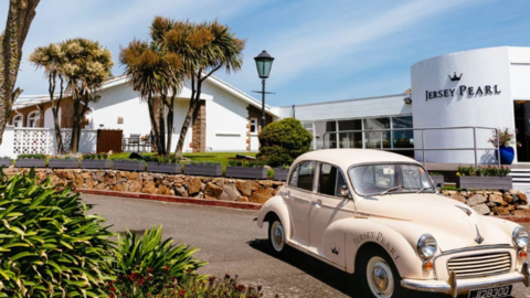 A shop and cafe with a Morris Minor car and palm trees.