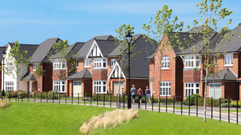 A computer-generate image of a row of red brick houses with a road in front and a grassy area in the foreground