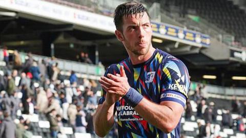 Niall Canavan, in Barrow's multi-coloured shirt, applauds fans as he leaves the field.