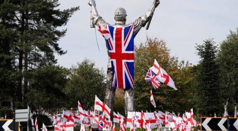 Flags are on a roundabout near a flag on a statue.