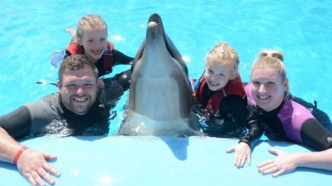 Laura Melling (left) and her family swimming with dolphins on a family holiday.