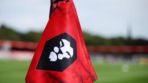 A corner flag at Salford City's Peninsula Stadium with the club's crest