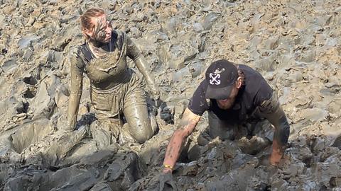 A woman and man crawl through river bank mud during the Maldon Mud Race 2026