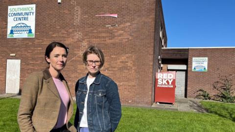 Kelly Brougham and Amy Swan stand in front of Southwick Community Centre which has laid empty for over a year. The grey metal shutters on the building remain firmly closed blocking access to the building.