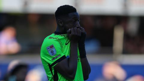 Portsmouth midfielder Ebou Adams looking dejected, holding his shirt up to his mouth in frustration after his side's 6-1 defeat at Queens Park Rangers.