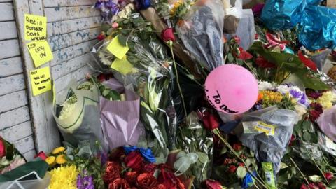 Floral tributes have been left near the scene of the crash. Messages have been stuck to the fence behind the flowers. One reads: "Rest in Paradise Devon" while another writes: "You will be missed". 