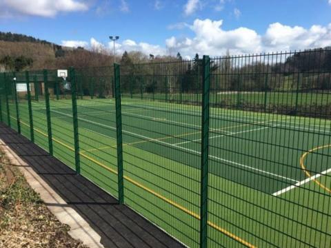 An image of the proposed new floodlit sports pitch at Worplesdon Primary School. Green fencing can be seen around the perimeter of the pitch.  