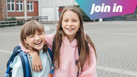 two girls wearing hoodies smiling