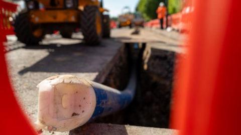 A water pipe sticks out of a road undergoing construction works. 
