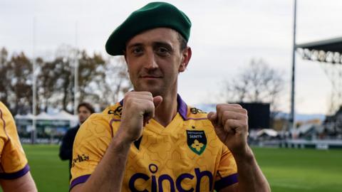 Northampton Saints scrum-half Alex Mitchell with both fists clenched in celebration and wearing a beret following their Champions Cup win in Pau