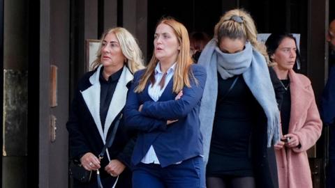 Roxanne Matthews, with long straight reddish brown hair, and Danielle Dowdall, with her blonde hair tied back and a scarf covering her face